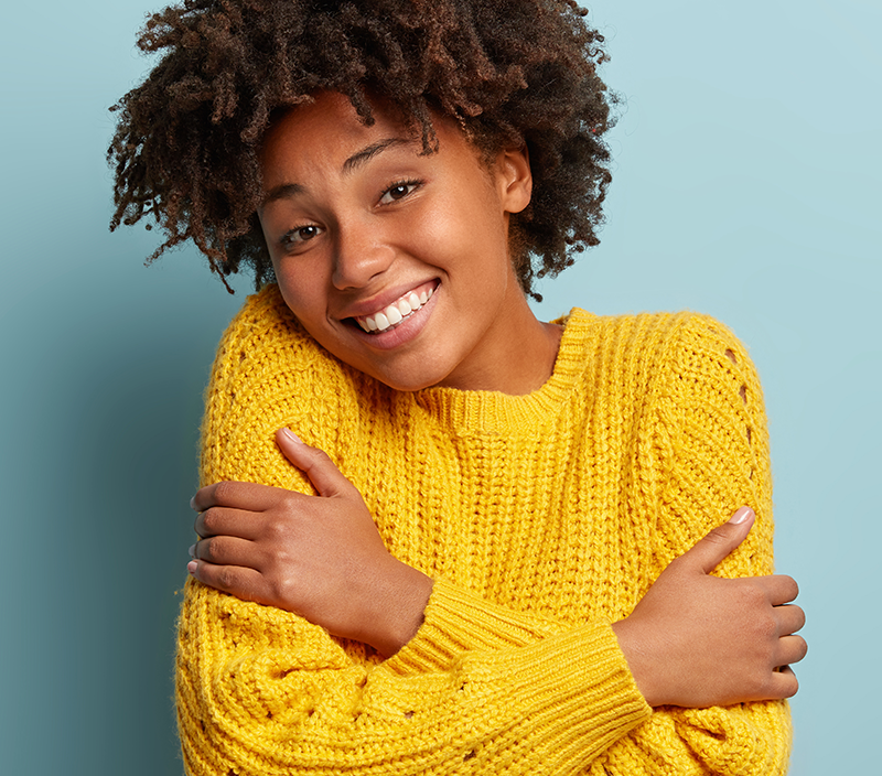 A woman hugging herself while smiling.