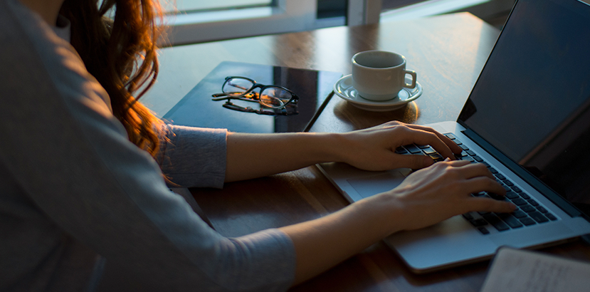 The arms and hands of a woman working on a computer.